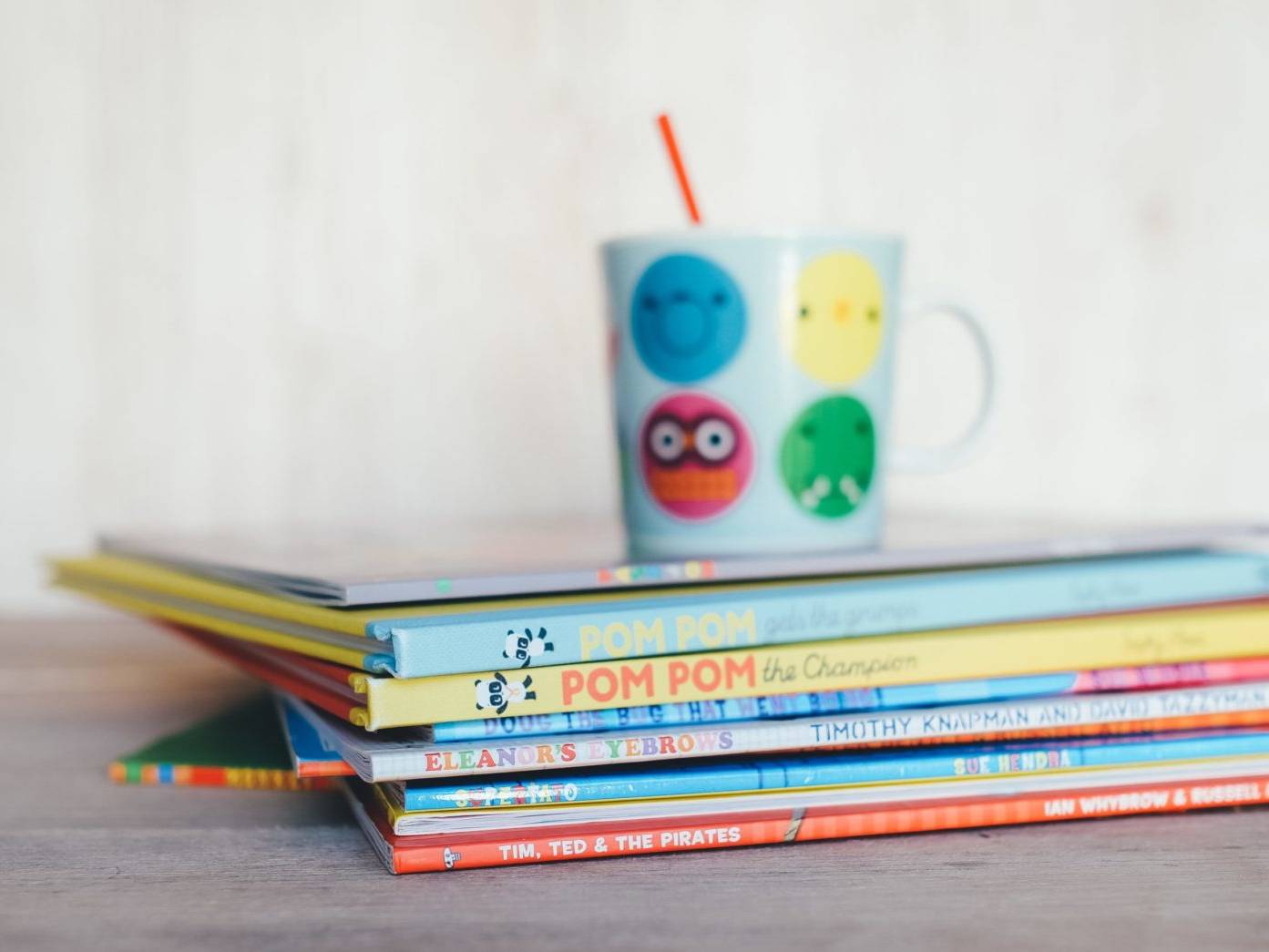children books in a pile with cup on top